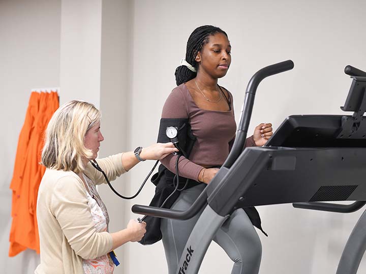 A faculty member measures the heart rate of a student on a treadmill