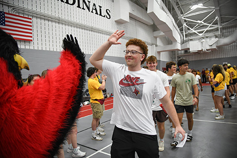 Cardinal welcomes students with a high-five during Welcome Weekend.