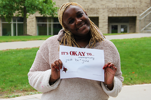 A member of the campus community holds up a message reading, 