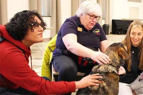 Students interact with Maverick the Therapy Dog during a visit to campus.