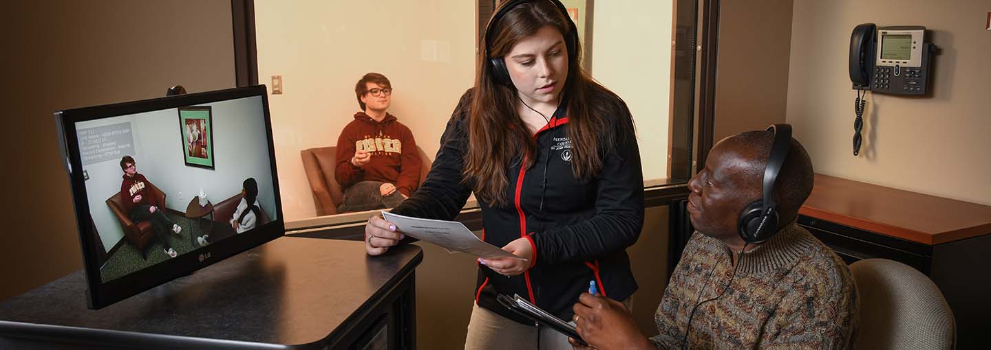 A student and faculty in the mental health counseling program observe a simulated session.