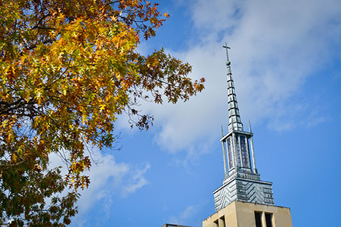 Kearney Steeple against blue sky and yellow leaves.