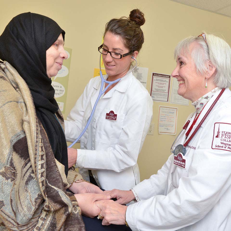 Nursing student and faculty mentor help a refugee patient.