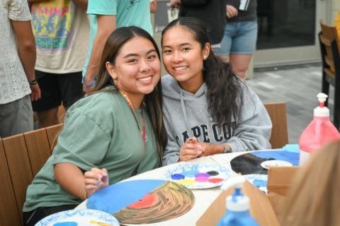 Students smile together while working on a craft project during Welcome Weekend.